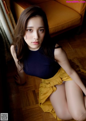 A woman in a black top and yellow skirt posing for a picture.