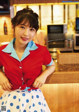 A woman in a red shirt and polka dot skirt posing for a picture.