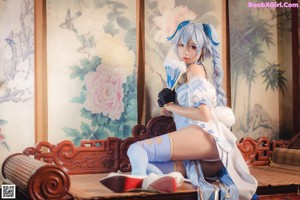 A woman in a blue and white outfit sitting on the floor.