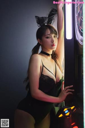 A woman in a black lingerie standing in front of a dart board.