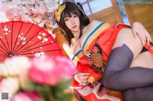 A woman in a red and blue kimono sitting on the ground.