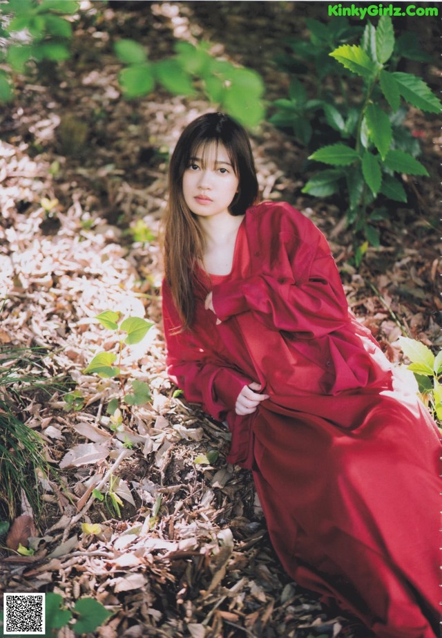 A woman in a red dress sitting on the ground.