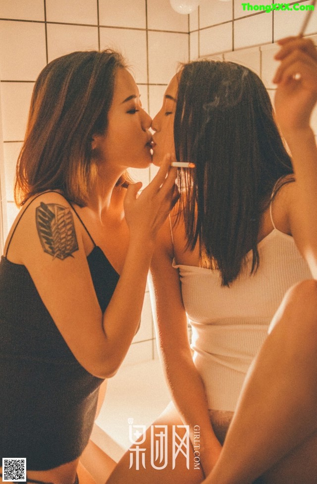 A woman is kissing another woman in front of a mirror.