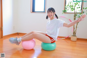 A woman in a white shirt and red shorts holding a hula hoop.