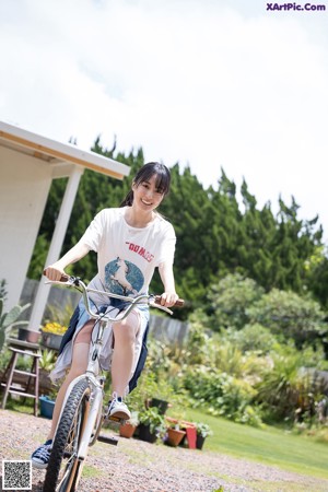 A woman in a blue and white shirt leaning against a fence.