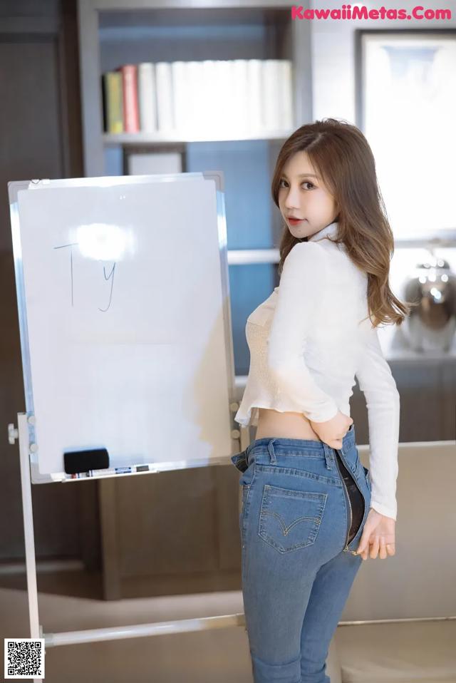 A woman standing in front of a white board with writing on it.