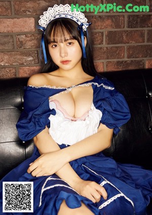 A woman in a maid outfit sitting on a couch.