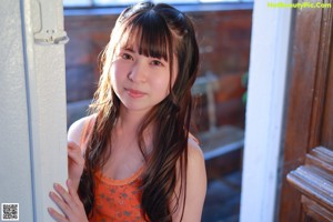 A young woman leaning against a white wall.