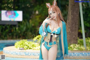 A woman in a bikini standing next to a swimming pool.