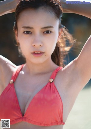 A young woman laying on the ground with her hands on her face.