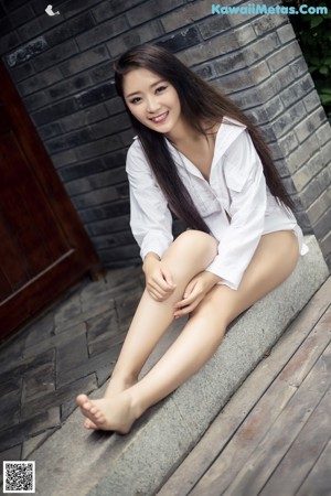 A woman in a white shirt and panties posing for a picture.