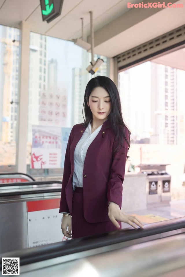 A woman in a business suit standing on a train.