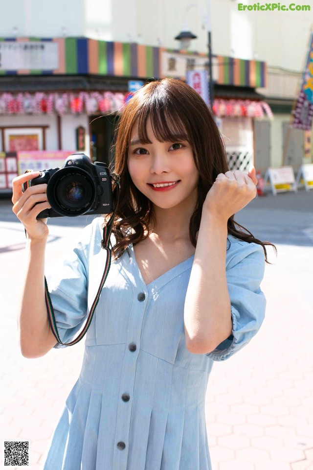 A woman in a blue dress holding a camera.