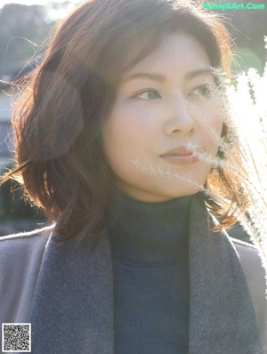 A woman in a blue turtle neck sweater standing on a train track.