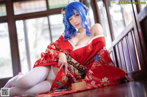 A woman in a red kimono sitting on a bed.