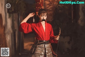 A woman in a red kimono holding a samurai sword.