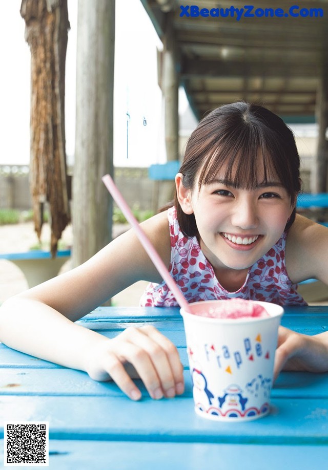 A young girl sitting at a table with a cup of ice cream.