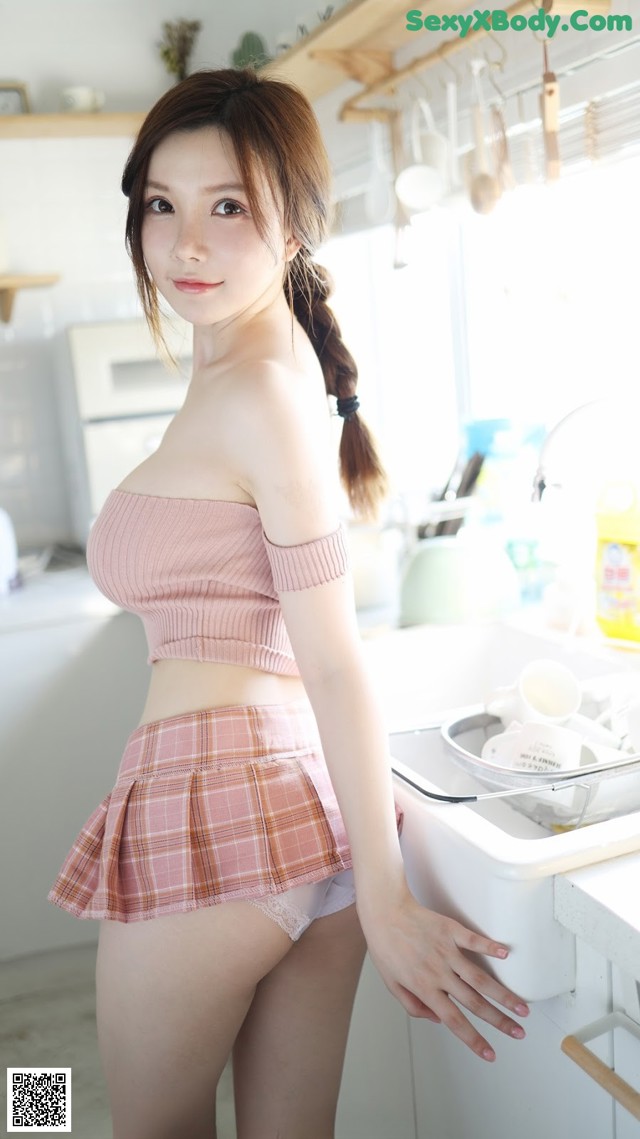 a woman in a pink top and skirt standing in a kitchen