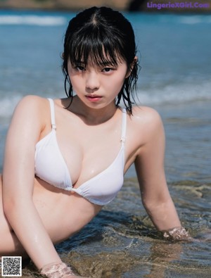 A woman in a white bikini standing on a beach.