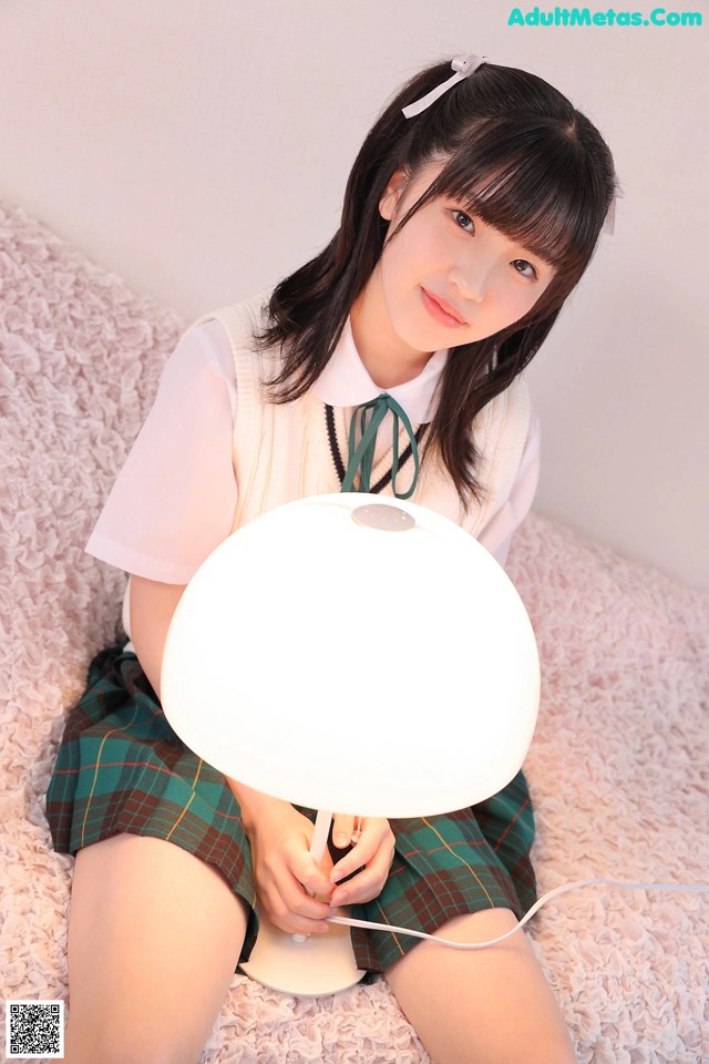 A young woman sitting on a bed holding a lamp.