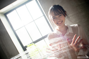 A woman wearing a white shirt standing in front of a window.