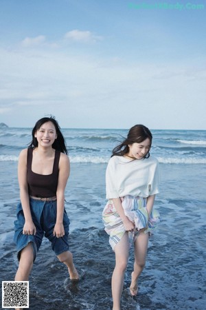 A couple of women sitting next to each other near a pool.