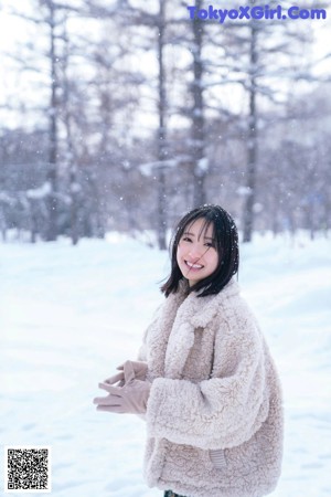 A woman in a white coat standing in the snow.