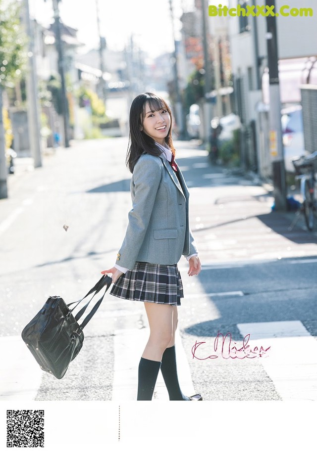 A woman in a school uniform is walking down the street.