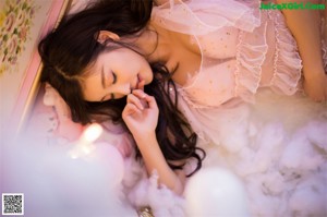 A woman in a white lingerie sitting next to a christmas tree.