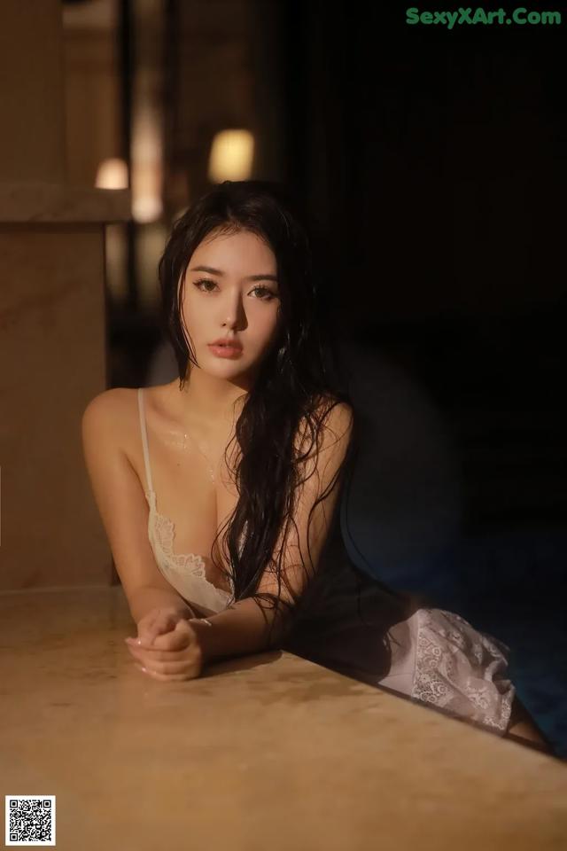 A woman in a white lingerie sitting on a table.