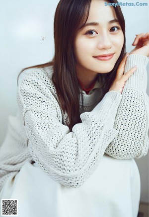 A woman sitting on top of a wooden dresser next to a dresser.