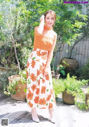 A woman in a white top and tan skirt posing for a picture.