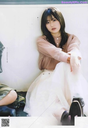 A woman sitting on the ground in front of a wall.