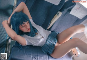 A woman with blue hair is sitting on an airplane.