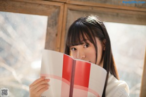 A young woman sitting on a couch reading a book.