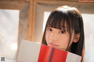 A young woman in a school uniform holding a book.